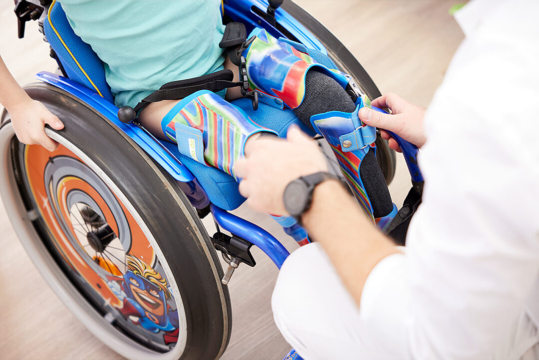 Technikerin stellt die Fußrasten am Kinderrollstuhl ein
