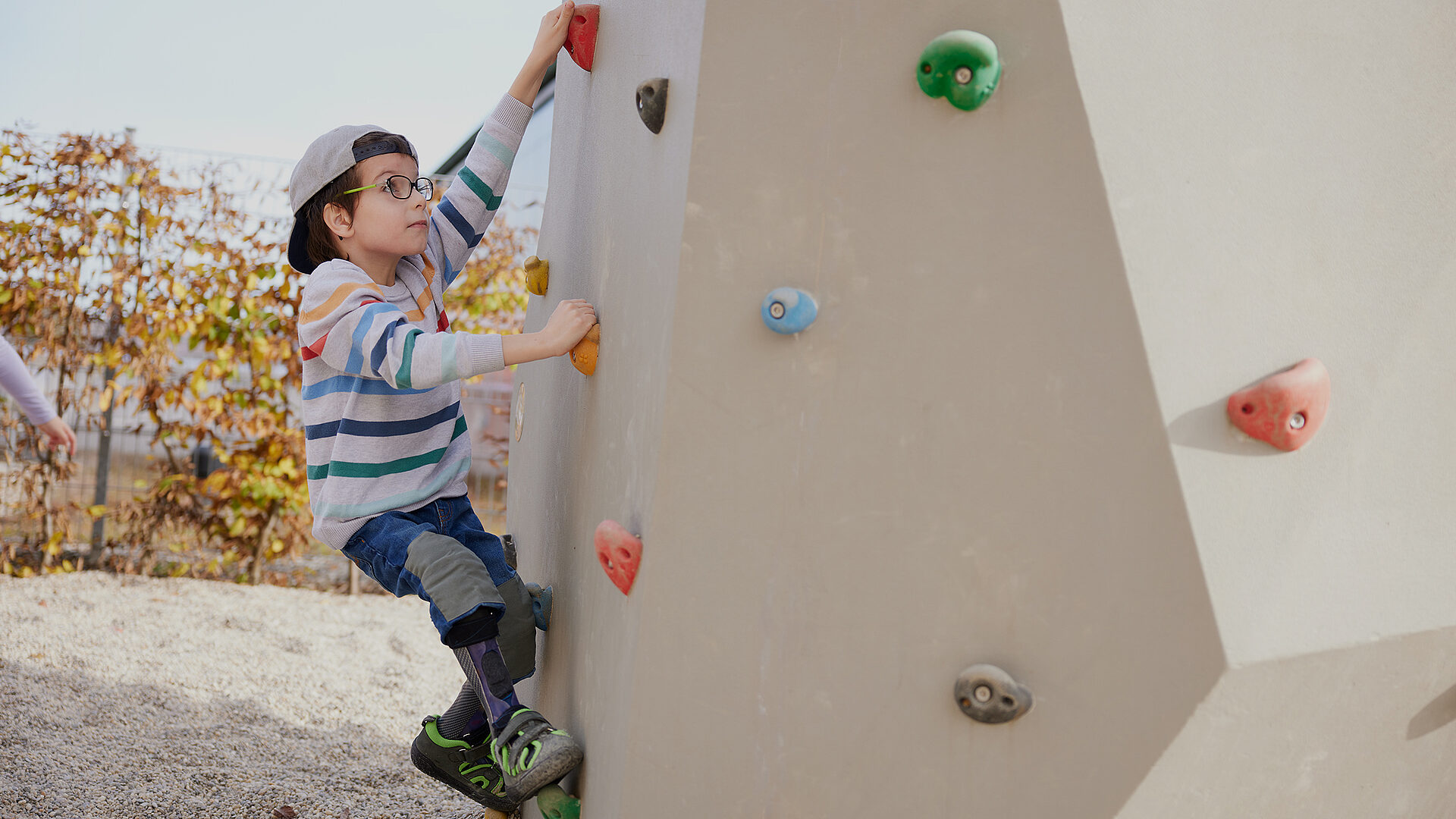 Benedikt klettert mit Orthesen an einer Kletterwand im Freien