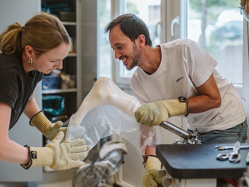 Zwei Orthopädietechniker arbeiten gemeinsam an einem Tiefziehmodell
