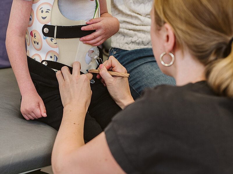 Orthopädietechnikerin passt einem Kind ein Korsett an