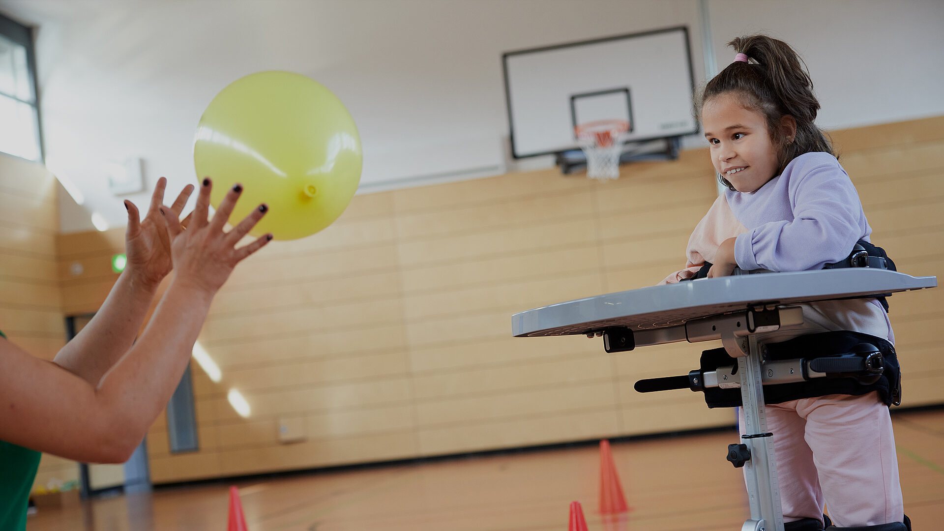 Denize spielt am Stehtrainer mit einem Luftballon in der Turnhalle