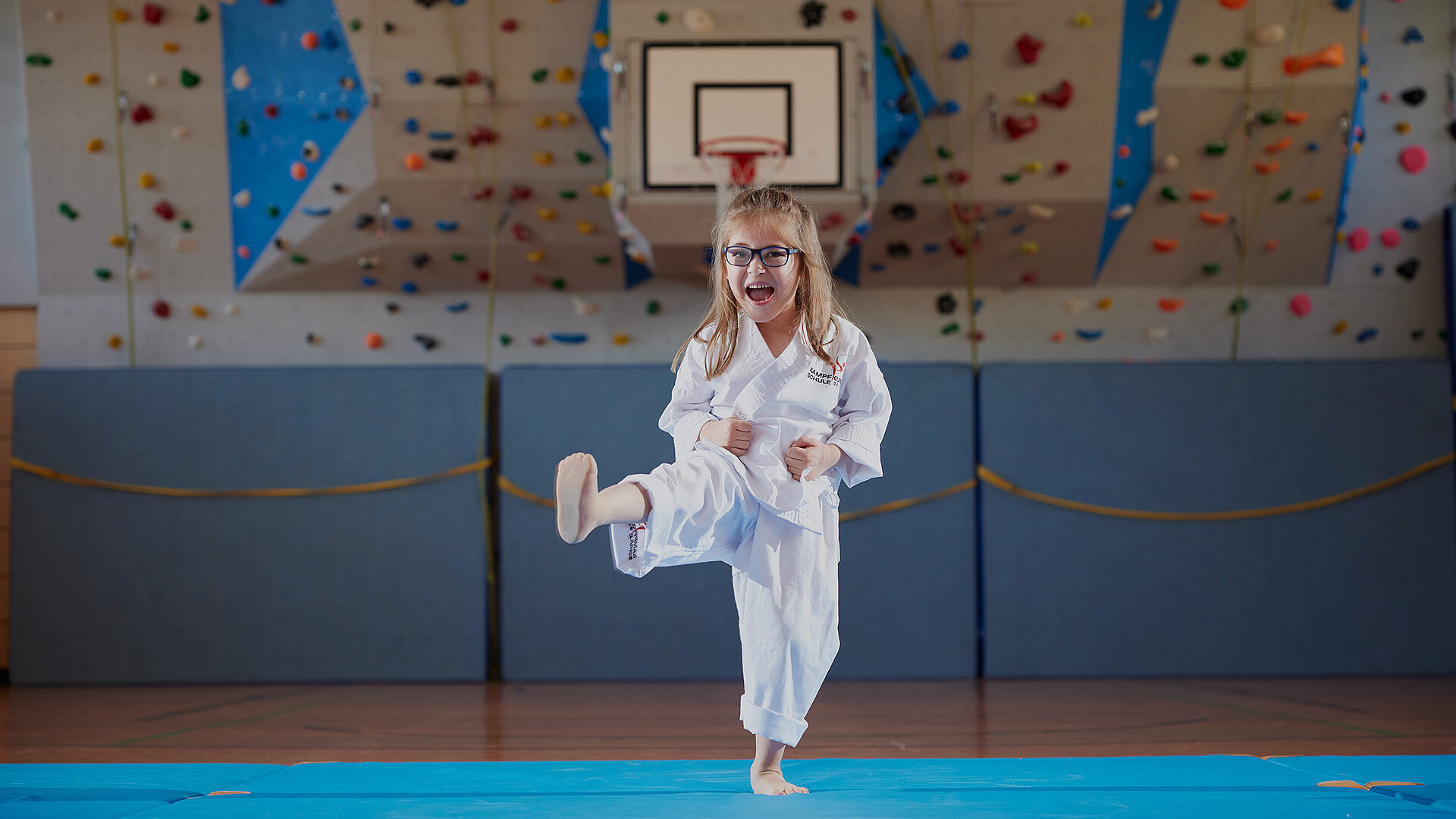 Myriam in Karate-Kleidung macht mit ihrer Beinprothese einen Kick in der Turnhalle