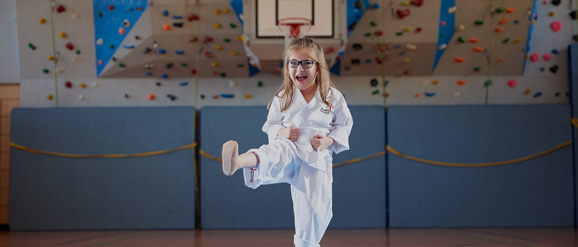 Myriam in Karate-Kleidung macht mit ihrer Beinprothese einen Kick in der Turnhalle