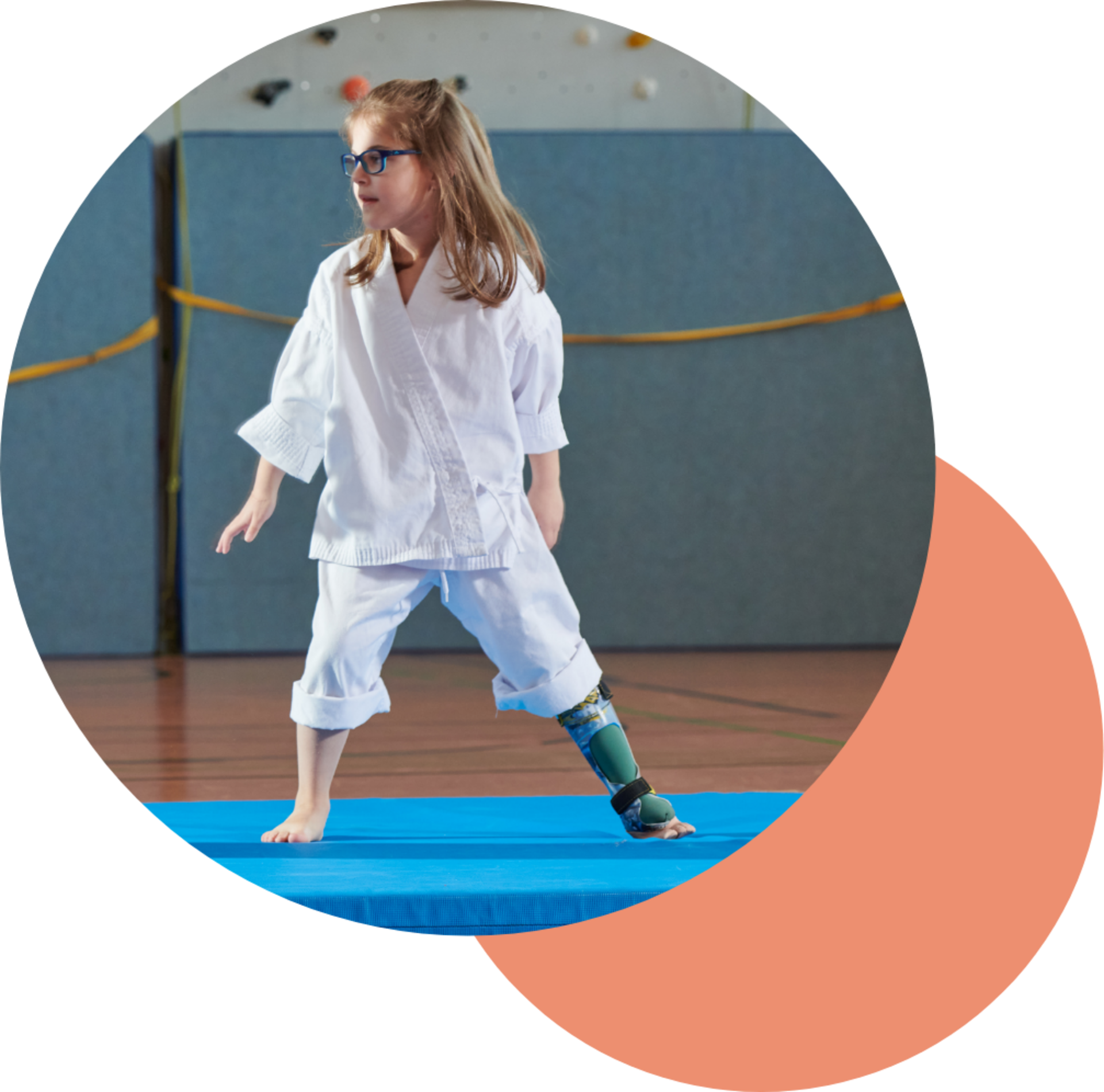 Mädchen in Karate-Kleidung mit Unterschenkelorthesen auf einer blauen Matte