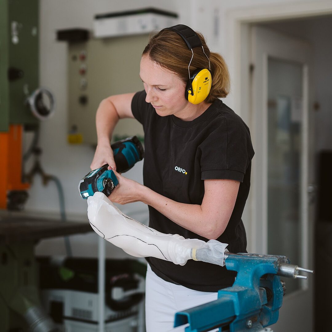 Orthopädietechnikerin mit Gehörschutz beim Schleifen in der Werkstatt